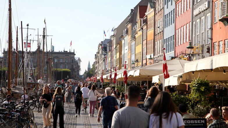 Passanten spazieren am Kopenhagener Nyhavn entlang, dem bei Touristen beliebten Hafen mit seinen bunten Häuschen.