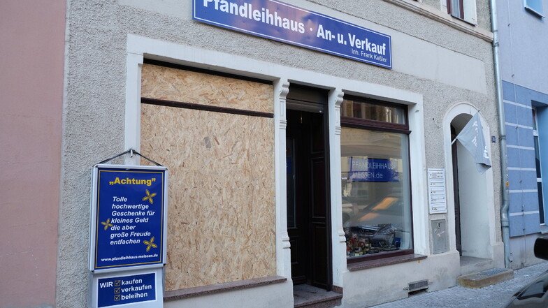 Eine Sperrholzplatte sichert das kaputte Schaufenster des Pfandleihhauses in der Meißner Neugasse. Ob es sich um einen gezielten Anschlag gehandelt hat, ermittelt die Polizei.