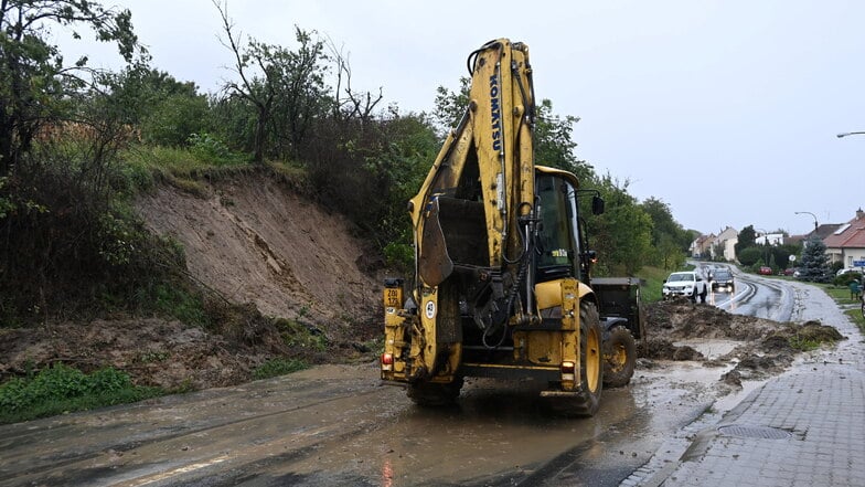 Tschechien, Bílovice: Mit einem Räumfahrzeug wird Erdreich von einer Straße geschoben, das wegen des anhaltenden Regens von der Böschung abgerutscht ist.