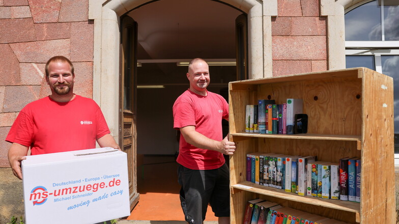 Florian Wolter (links) und Daniel Riege, Mitarbeiter der Firma MS Umzüge, räumen Bücher in das Übergangsdomizil der Roßweiner Bibliothek an der Döbelner Straße 58 – gegenüber dem Lidl-Markt ein.
