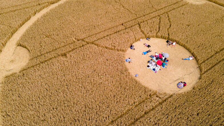 Menschen laufen durch einen Kornkreis in einem Weizenfeld.