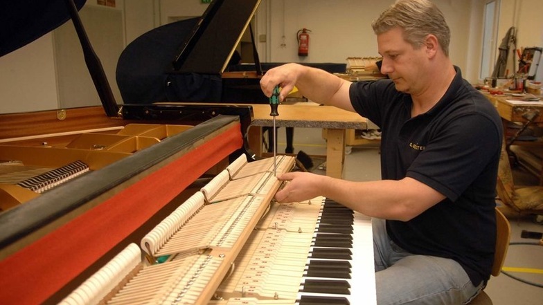 Klavierbauer Maik Tusche beim Ausarbeiten – dem letzten Feinschliff – an einem Flügel.