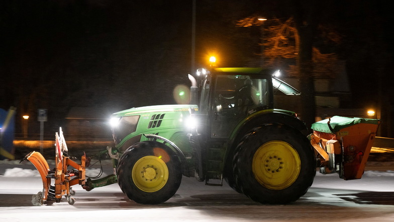 Ein Traktor mit einem Schneeschild räumt einen Parkplatz in Dippoldiswalde.