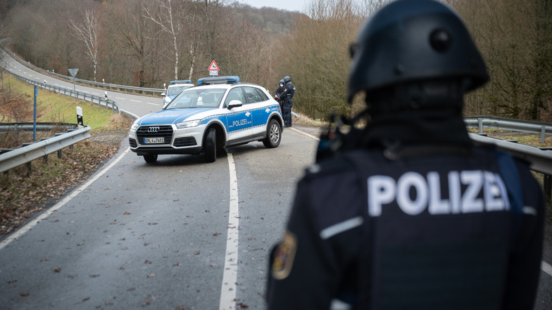 Polizeibeamte stehen an einer Absperrung an der Kreisstraße 22, rund einen Kilometer von dem Tatort entfernt, an dem zwei Polizeibeamte durch Schüsse getötet wurden. Sie sperrten die Straße am Montag für den Verkehr.
