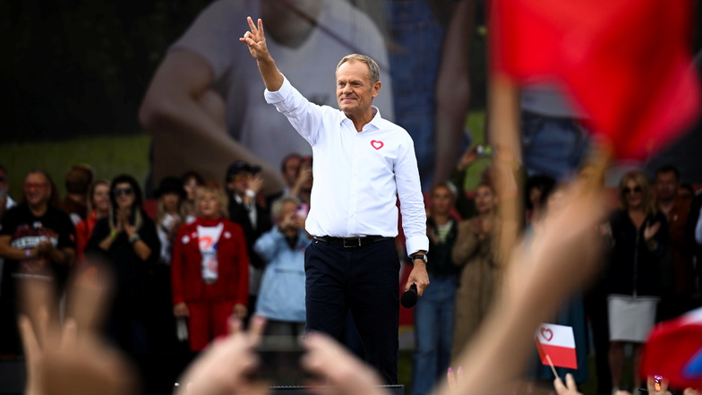 Oppositionsführer Donald Tusk zeigt ein Friedenszeichen, während er auf einer Bühne in Warschau spricht.