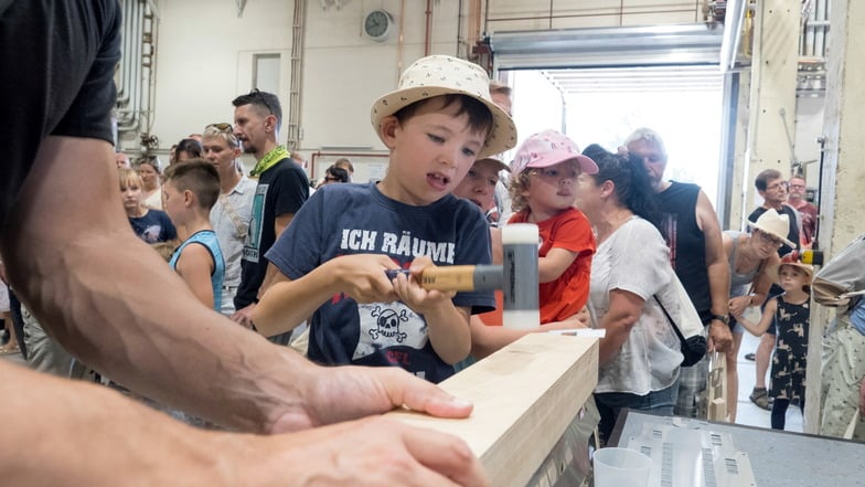 Der siebenjährige Theo biegt mit einer Holzform und einem Hammer in einer Fertigungshalle einen Waggon zurecht.