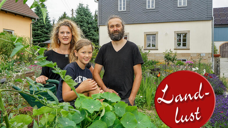 Janine und Mario Werab stehen mit Tochter Lilian im Bauerngarten vor dem sanierten Wohnhaus in Schmiedefeld.