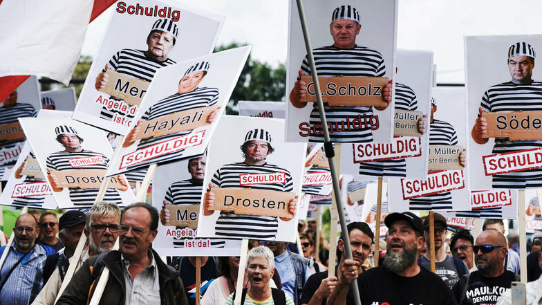 Teilnehmer einer Demonstration gegen die Corona-Maßnahmen halten am 29. August 2020 Schilder mit Fotomontagen von Politikern, Journalisten und Wissenschaftlern jeweils mit Namen, in Sträflingskleidung und dem Wort "Schuldig".