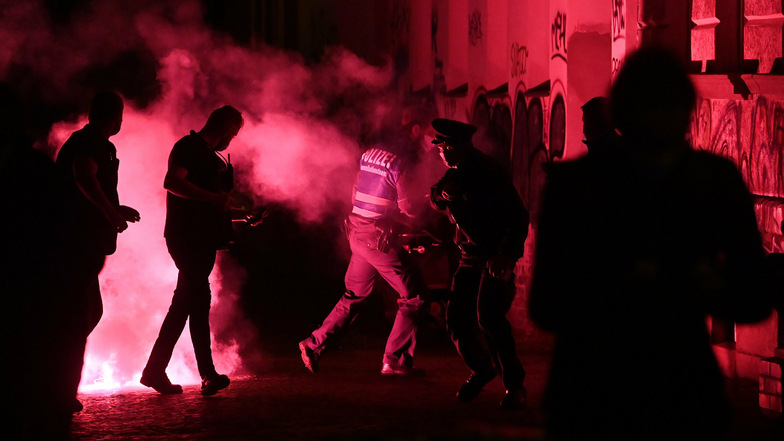 Polizisten laufen von der Stelle weg, an der zuvor bei einer Demonstration im Stadtteil Connewitz eine rote Pyro-Fackel explodiert war.