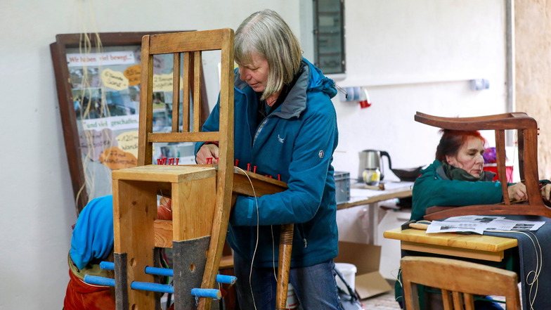 Waltraud Hartwig zeigt Teilnehmern der Mitwach-Werkstatt, wie sie Stühle reparieren.