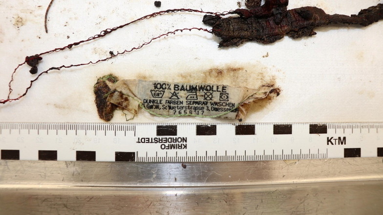 Das Etikett und Stoffreste, die bei dem Skelett gefunden wurden.