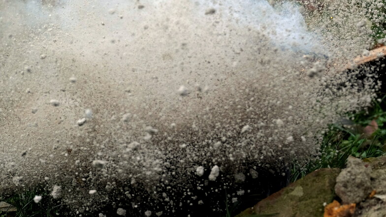Das Bild zeigt die nachgestellte Explosion eines Böllers in einem mit Kies gefüllten Eimer.