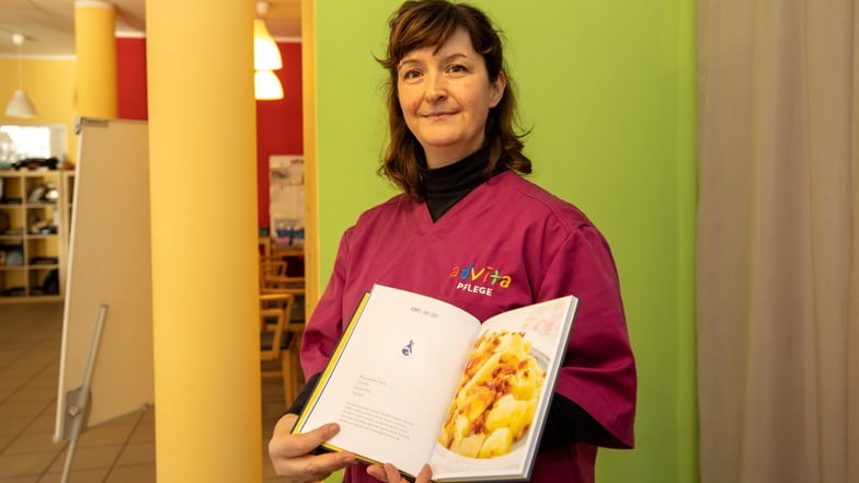 Pflegekraft Sandra Höher zeigt ein Kochbuch, das der Advita Pflegedienst an Klienten verschenkt.
