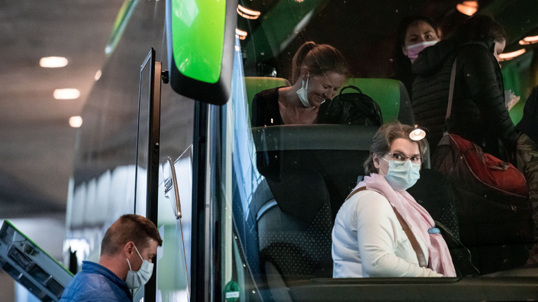 Nordrhein-Westfalen, Düsseldorf: Erntehelfer sitzen mit Mundschutzmasken in einem Bus am Ankunft-Terminal. Die Landwirte bezahlen die Flüge, die zu Sonderkonditionen angeboten werden. Die Saisonarbeiter müssen sich einem Gesundheitscheck unterziehen.