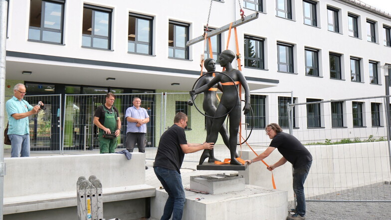 Wieder komplett: Frank Hempel (li.) und Vinzenz Schmidt vom Unternehmen Ostmann + Hempel montieren die Skulptur "Reifenspielende Mädchen" am alten Standort vor der Oberschule Am Merzdorfer Park. Die wird erst in den Sommerferien bezogen.
