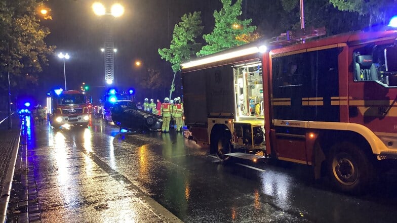 Ein Auto bleibt nach einem Unfall in Dresden auf dem Dach liegen. Die Feuerwehr ist im Einsatz.