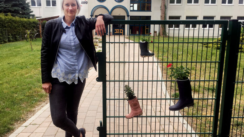 Kati Ide, stellvertretende Leiterin der Kita „Am Elsterbogen“, am Eingangstor, das mit bepflanzten Gummistiefeln geziert ist.
