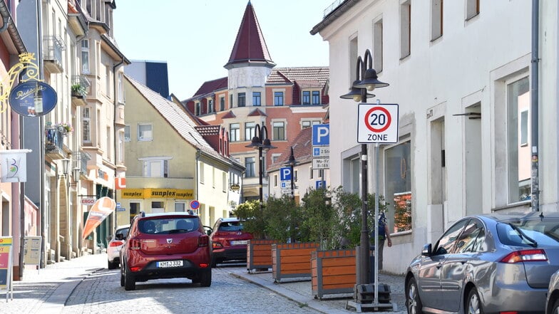 Tempo 20 auf der Hauptstraße - der Verkehrsversuch erhitzt die Gemüter. Wegen Blumenkübeln in den Haltebuchten halten Lastwagen auf der Straße oder dem gegenüberliegendem Fußweg.