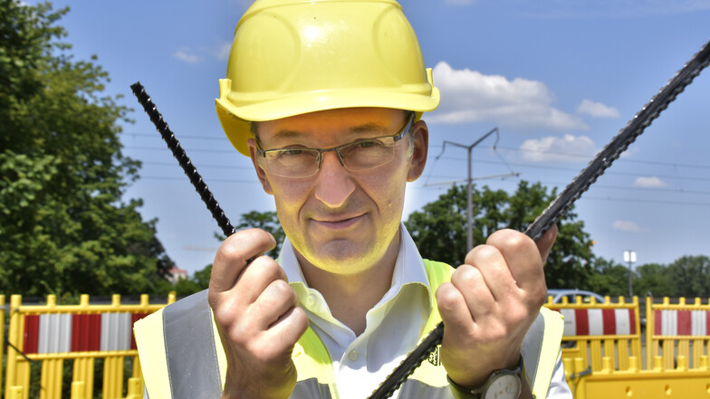 Straßenbauamtschef Franke zeigt jeweils einen Carbon- (l.) und einen Basaltstab der neuen Bewehrung für die Fuß- und Radwegplatte.