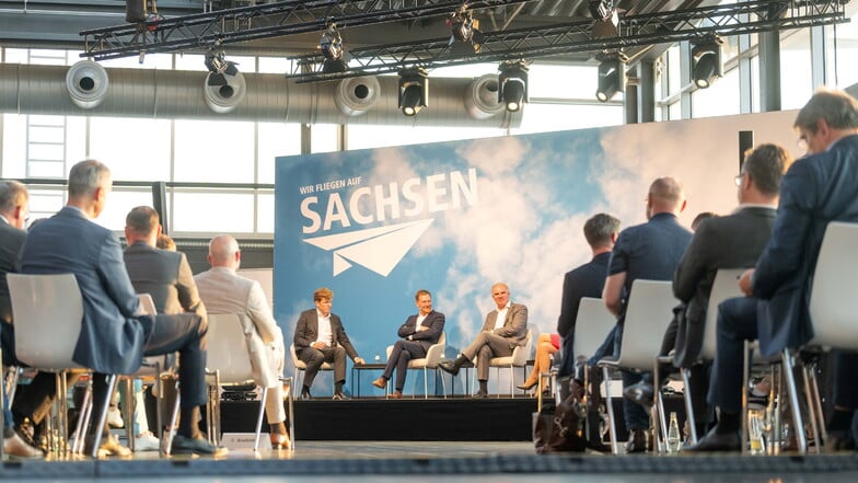 Götz Ahmelmann, Vorstandsvorsitzender der MFAG, Sachsens Ministerpräsident Michael Kretschmer und Lufthansa-Chef Carsten Spohr (hinten, v.r.n.l.) im Trialog im Dresdner Flughafen-Terminal.