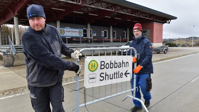 Sylvio Wartmann (re.) und Johannes Hoogervorst, Mitarbeiter der Stadt Altenberg, bauen am Parkplatz an der Zinnwalder Grenzzollanlage die Beschilderung für den Bobbahn-Shuttle auf.