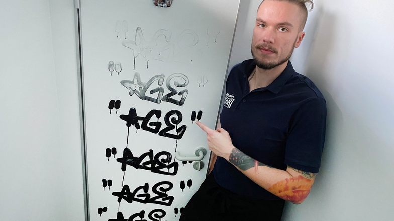 Henry Grohmann, der Sohn von Inhaber Ralph Grohmann, zeigt die rätselhaften Graffiti-Schmierereien an der Toilettentür des Restaurants Captain Hook am Olbersdorfer See.