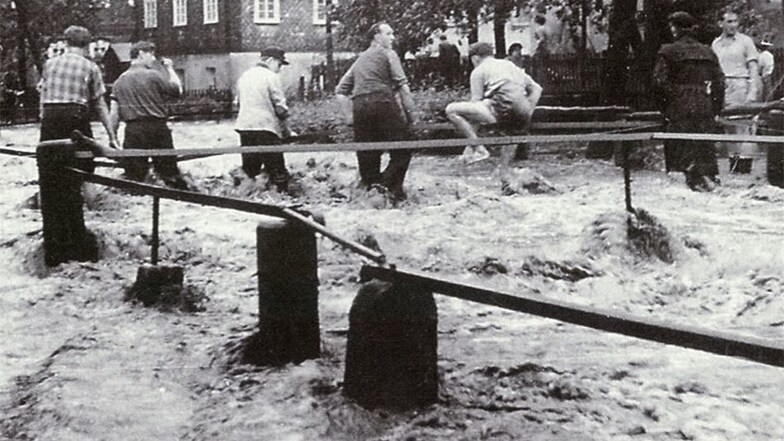 In Cunewalde, das damals zum Kreis Löbau gehörte, waren am 28. Juni 1958 schwere Wolkenbrüche niedergegangen. Die Straßen wurden zu Flüssen. Die Erinnerung an dieses Ereignis wurde mit diesem und anderen Fotos im Bildband „Vu Hoalbendurf bis a de Hoalbe“ 