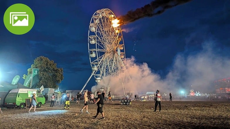 Besucher des Highfield-Festivals und Helfer blicken am 17. August auf das Riesenrad, an dem Flammen zu in zwei Gondeln sehen sind.