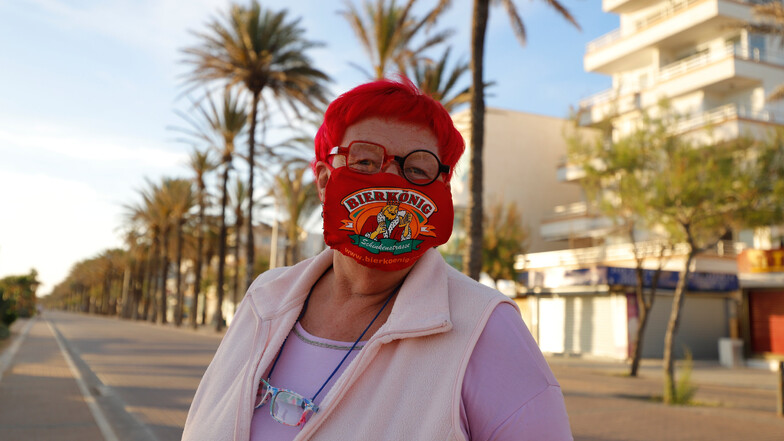 Heti Hartl steht mit einer Maske, die von einer der berühmtesten Bierkneipen (Bierkönig) gesponsored wird, am Strand El Arenal in Palma de Mallorca.