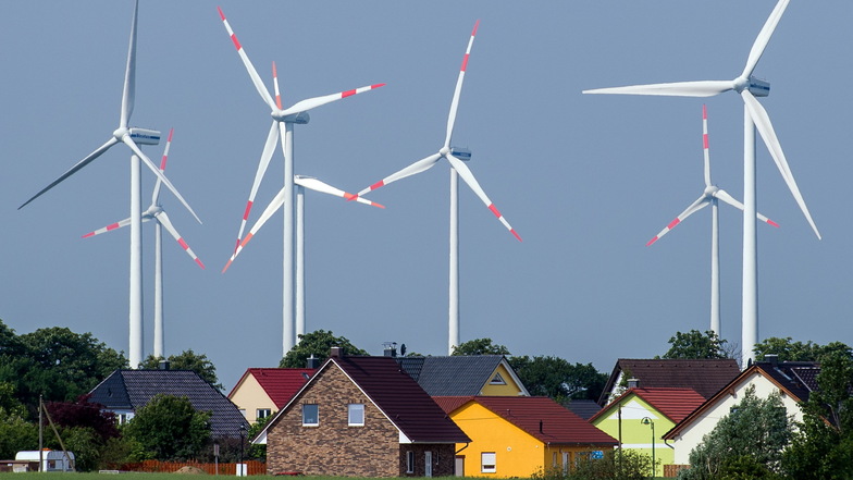 Dicht stehen die Windräder eines Windenergieparks an Einfamilienhäusern. Wie stehen die Parteien zu Wohnen und Klima?