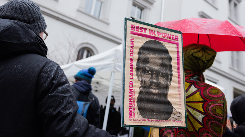 Demonstranten stehen mit Plakaten, die das Portrait des 16-jährigen Senegalesen Mouhamed Drame zeigen, vor dem Landgericht.