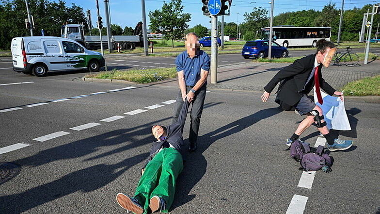 Ein Autofahrer zog zwei Klimademonstranten in Dresden auf den Bürgersteig. Doch ohne Erfolg. Sie setzten sich sofort wieder zurück auf die Straße.