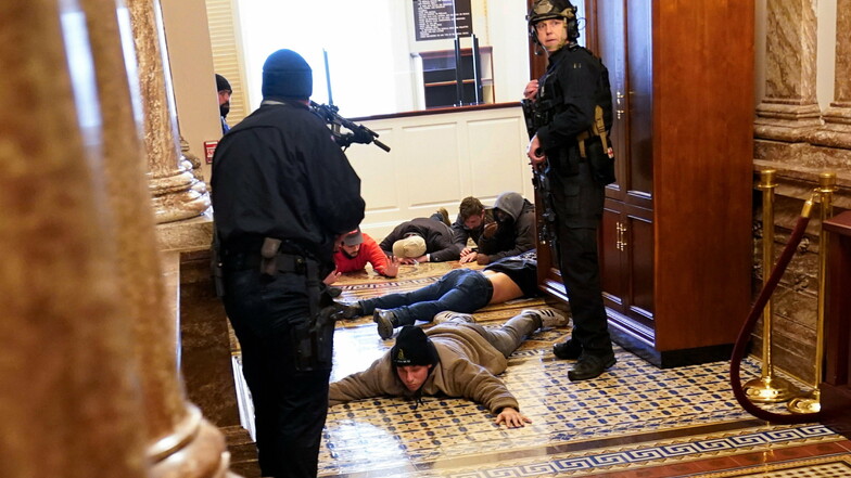 Die US-Kapitol-Polizei hält Demonstranten mit vorgehaltener Waffe fest.