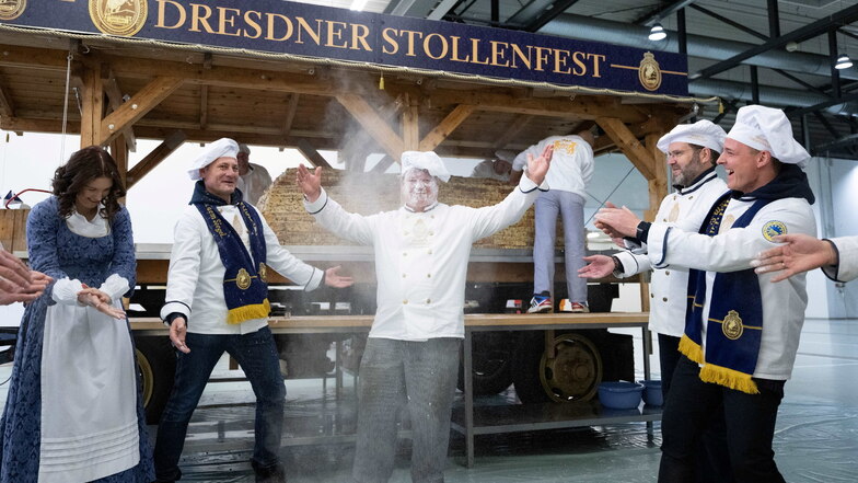 Karsten Liebscher (M), Bäckermeister, wird bei einem sogenannten "Puderzuckermoment" von den Bäckern des Schutzverbandes Dresdner Stollen vor einem Riesenstollen in einer Messehalle mit Puderzucker beworfen.