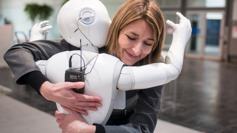 Die Kommunikationsmanagerin der Mitherstellerfirma Aldebaran, Aurora Chiquot, umarmt am 13. März 2016 auf dem Messegelände der CeBIT Hannover den humanoiden Roboter "Pepper".