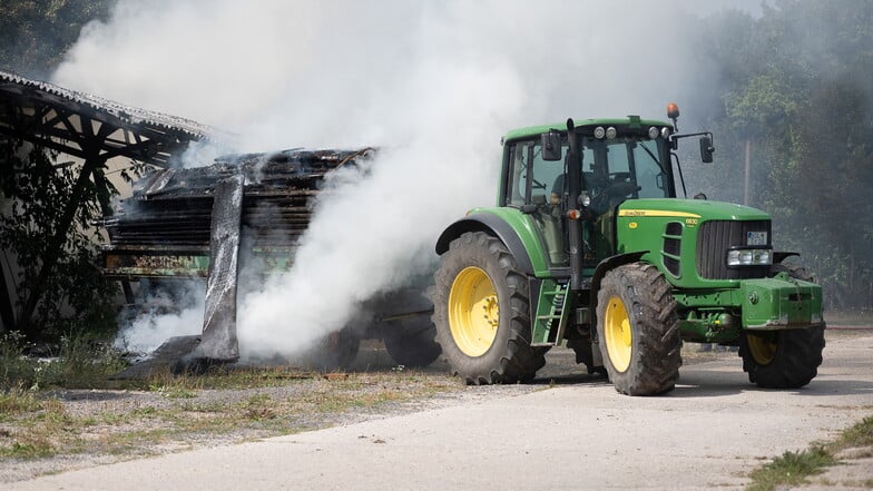 Brennendes Holz, das auf einem Anhänger lagerte, wird mit einem Traktor geborgen.