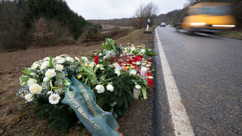 Blumen und Kerzen stehen am Tatort, an dem zwei Polizeibeamte bei einer Verkehrskontrolle erschossen wurden. Mittlerweile werden neue Details zur Tat und den mutmaßlichen Tätern bekannt.