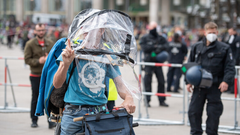 Auf dem Alexanderplatz in Berlin steht ein Demonstrant mit einer Schutzkonstruktion und einem Q. Das Q steht für QAnon und ist ein Zeichen einer Verschwörungstheorie.