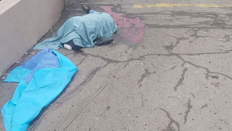 Leichen von Zivilisten liegen notdürftig mit einer Decke zugedeckt am Rand eines Fußweges in einer Stadt an der Fernverkehrsstraße von Sarny nach Kiew.