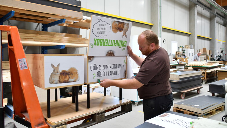 Grafiker Stephan Hochmann aus Radeberg beklebt Ladenmöbel in der Produktionshalle der Linovag. Hier Grünabfall-Sammelbehälter für die Gemüseabteilungen.