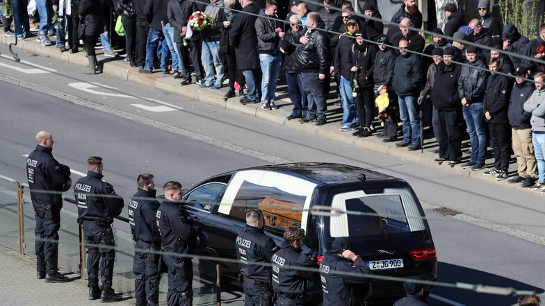 Teilnehmer des Trauerzugs sehen zum Leichenwagen mit dem Sarg von Thomas H.