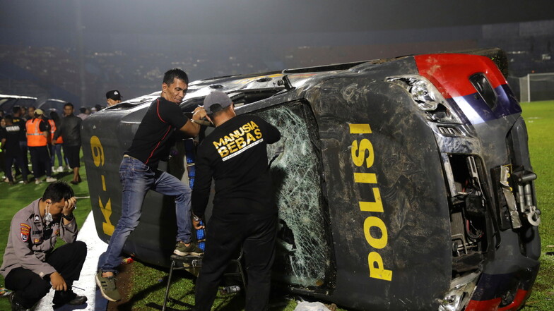 Beamte untersuchen nach den Zusammenstößen ein beschädigtes Polizeifahrzeug