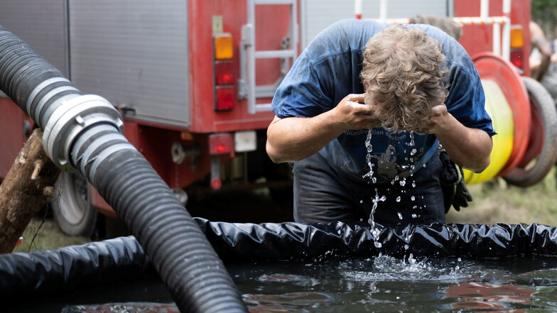 Ein Feuerwehrmann erfrischt sich an einem Löschwasser-Bassin.