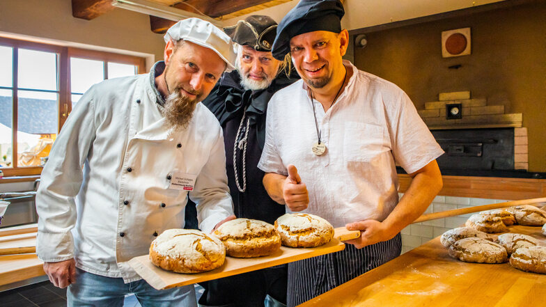 Bäckermeister Rico Ziegenbalg (re.) hatte schon Krabat-Mühlen-Brote gebacken, als Bäckermeister Michael Schlappa aus Räckelwitz (li.) im Namen der Bäckerinnung gratulierte. Auch der Schwarze Müller war an diesem Tag dabei.