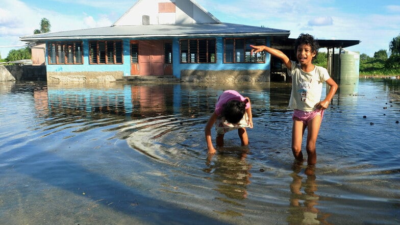 Kinder spielen einem vom Meerwasser steigenden überflutetem Platz in Funafuti, der Hauptstadt von Tuvalu.