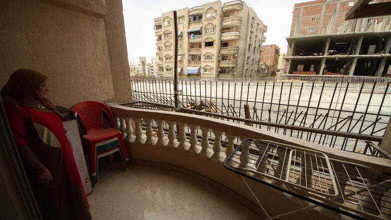 Eine Frau steht in Giseh auf dem Balkon ihrer Wohnung und blickt auf einen neu errichteten Brückenabschnitt der direkt an Wohnhäusern im Bezirk Al Omraniya vorbei führt.