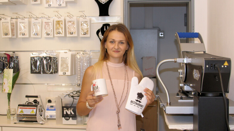Natalie Kraft in ihrem neuen Laden in der Elbgalerie Riesa. Hier kann sie unter anderem Tassen bedrucken (kleines Gerät hinten links) oder mit der Presse rechts Schriftzüge einprägen.