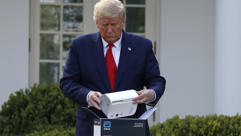 Donald Trump öffnet im Rosengarten des Weißen Hauses eine Verpackung mit einem Schnelltest für COVID-19. Im Kampf gegen das Coronavirus haben die USA inzwischen nach Trumps Angaben mehr als eine Million Menschen auf den Erreger getestet.