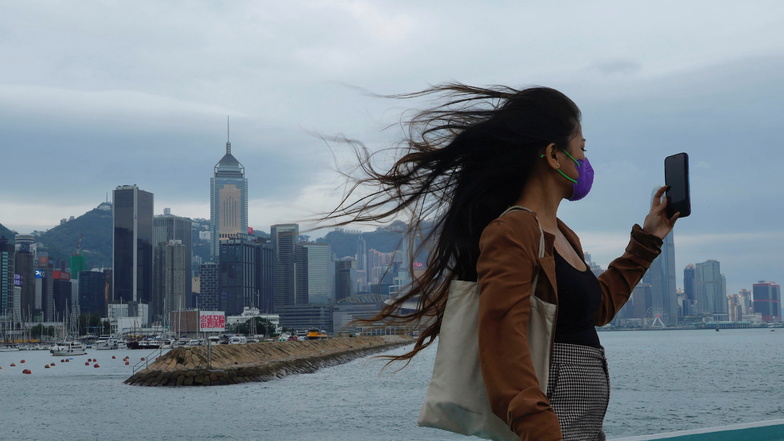Hongkong: Eine Frau macht bei starkem Wind ein Selfie am Victoria Harbour, während sich ein Taifun Hongkong nähert. Warum fotografieren sich so viele Menschen selbst?