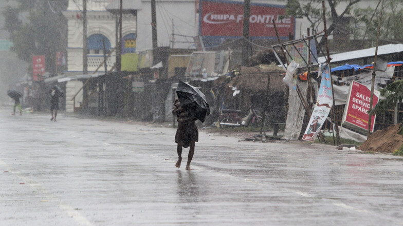 Ein Passant im indischen Chandbali schützt sich mit einem Regenschirm vor den Wassermassen.